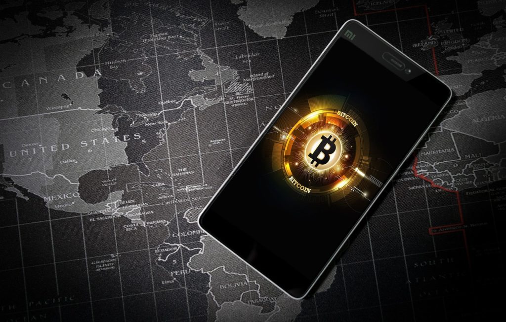 pay the ransom - image of mobile phone with bitcoin image overlaid on global map